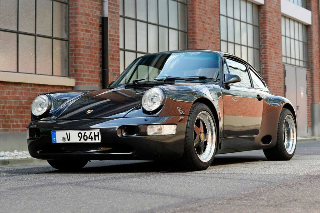 Dieses Foto zeigt den Porsche 964 Carrera 4, einen Oldtimer aus dem Jahr 1989, der aktuell bei My Next Classic zum Verkauf angeboten wird. Es handelt sich um ein Einzelstück, das vom bekannten Porsche-Tuner "Strosek" veredelt wurden. Das Coupé verfügt u.a. über 300 PS, Allrad-Technik, Handschaltung und eine 3,6 l Maschine.